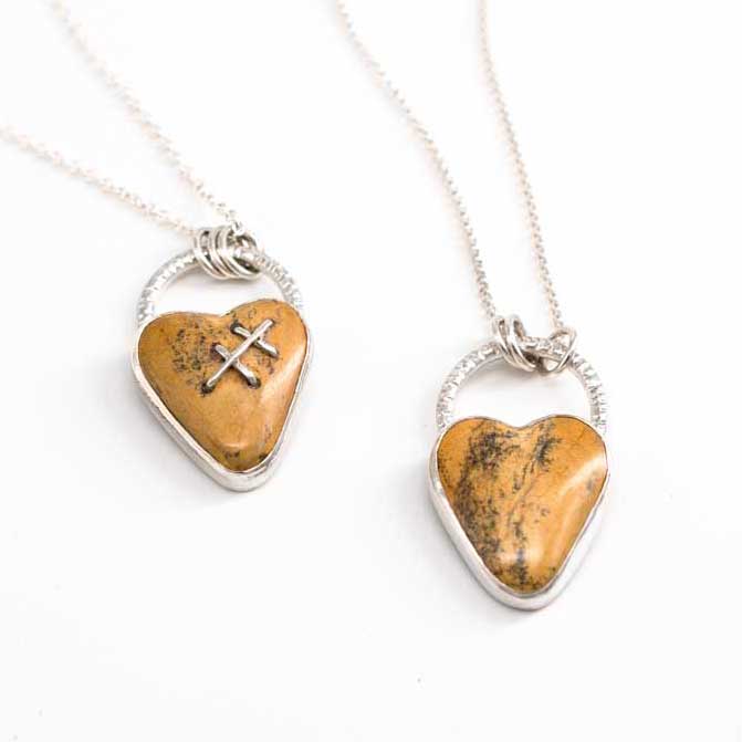 Two heart-shaped pendants on silver chains made from a yellow natural rock