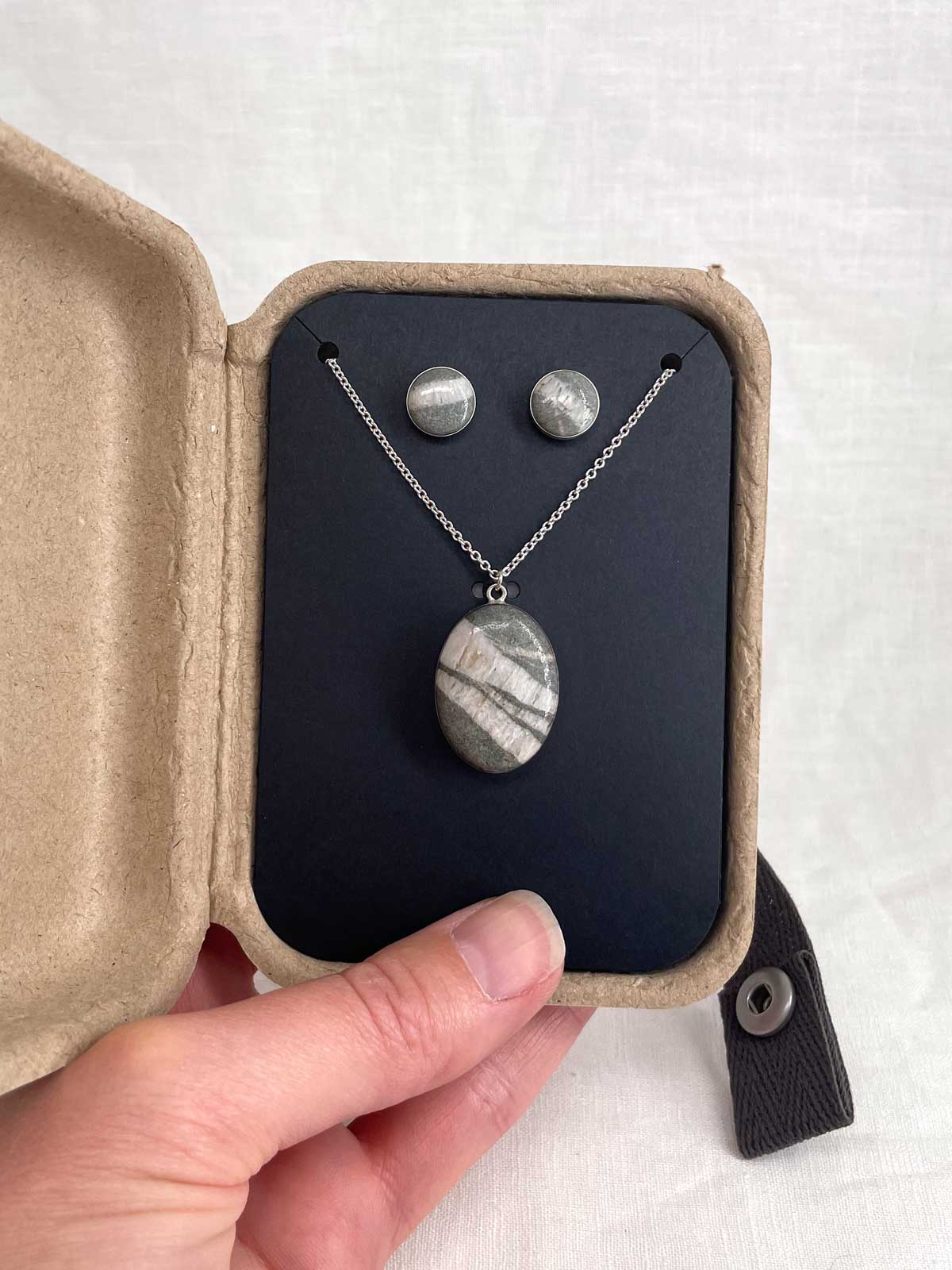 Jewelry set with necklace and earrings made from the same chunk of marble, displayed in a kraft gift box