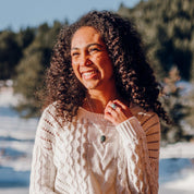 A smiling woman with long curly hair wears custom stone jewelry