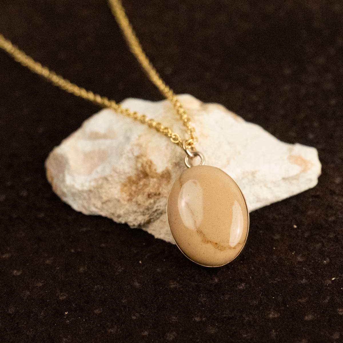 A cream-colored natural stone turned into a gold stone pendant necklace
