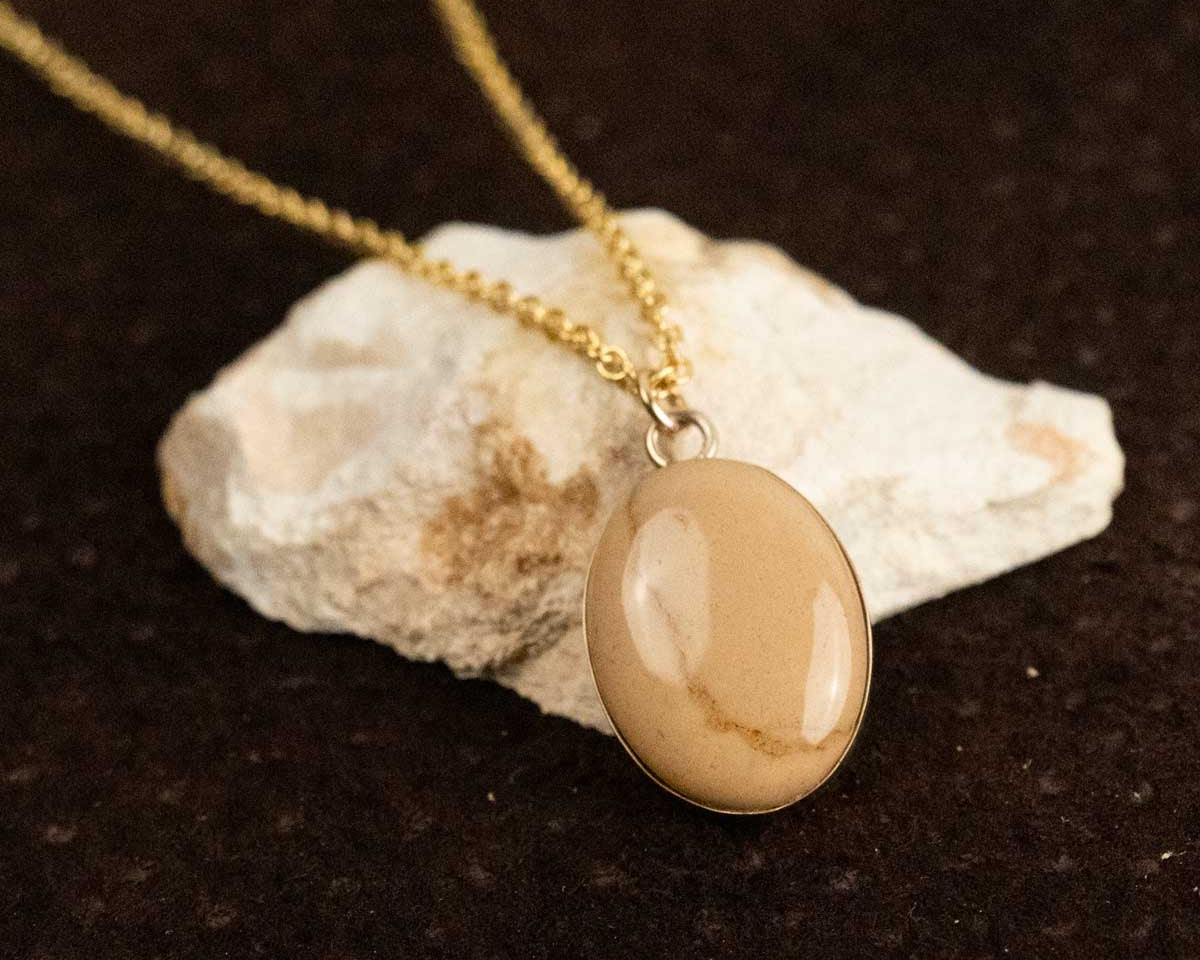A cream-colored natural stone turned into a gold stone pendant necklace