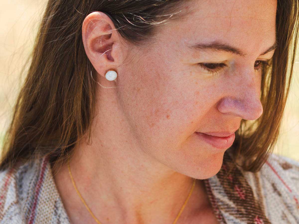 Leslie wears a pair of white marble stud earrings set in 14k gold fill