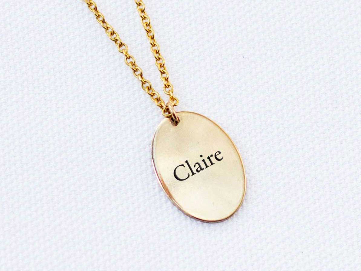 A 14k gold fill charm necklace engraved with the name Claire