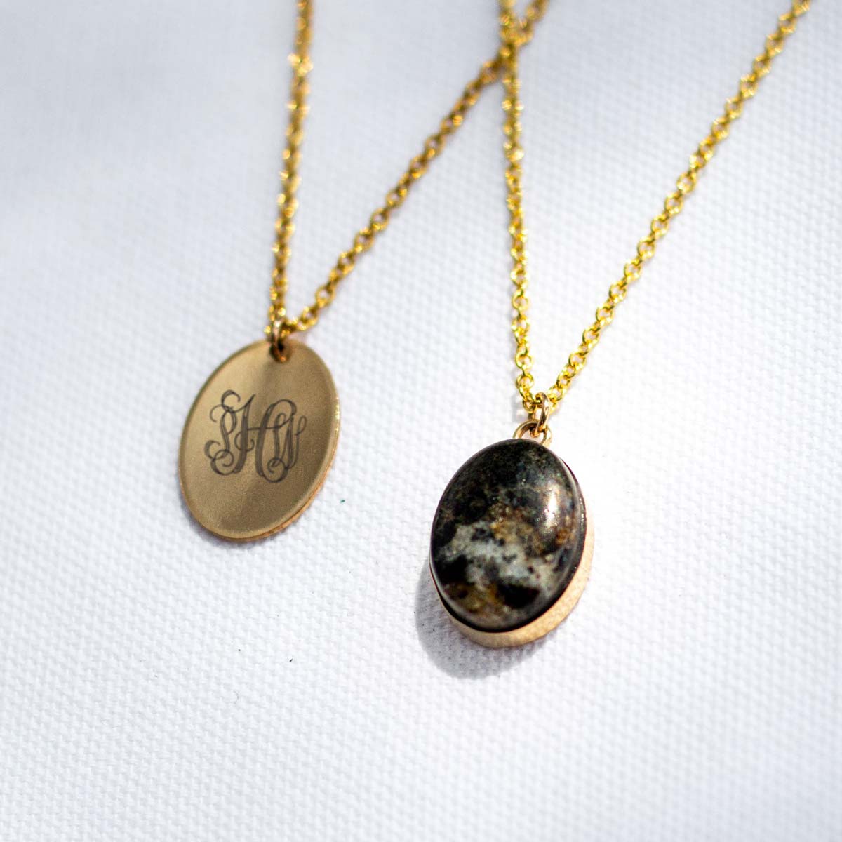 A gold charm and a stone pendant set in gold, both made with 14k gold fill