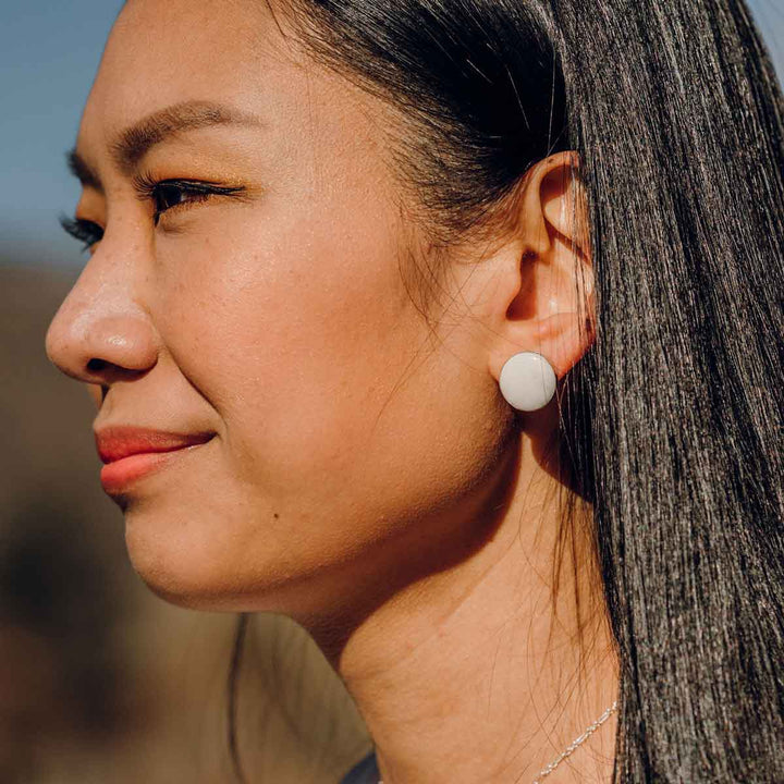 Woman with long black hair wears nickel-size white stone earring