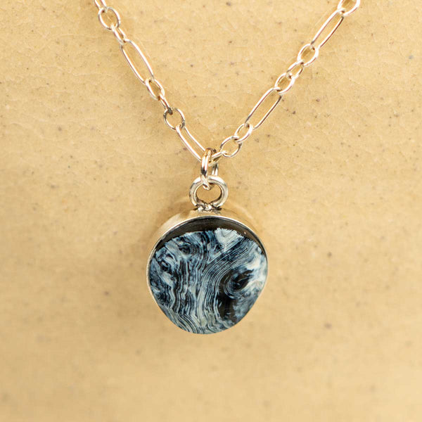 Necklace with a round agate pendant with a black and white striped pattern on a sterling silver long-short chain