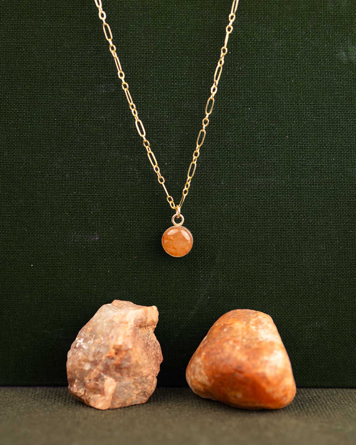 14k gold fill necklace with a round orange stone pendant on a long-short chain