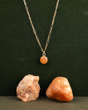 14k gold fill necklace with a round orange stone pendant on a long-short chain