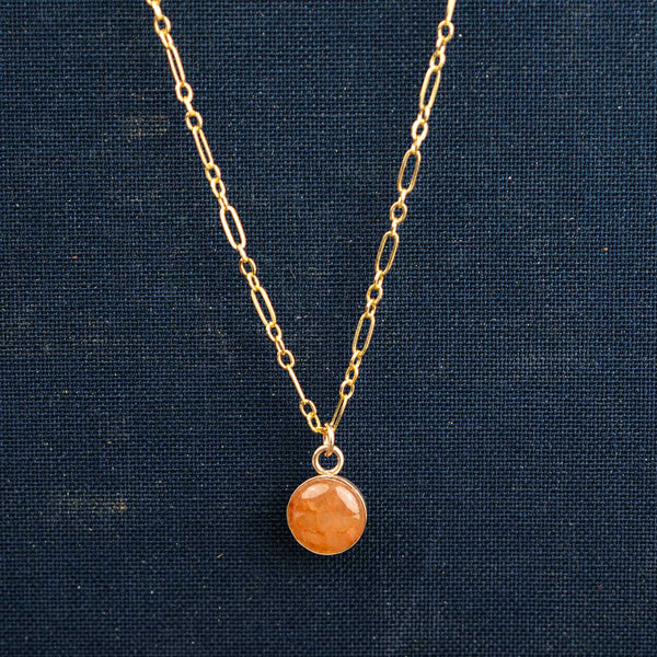 14k gold fill necklace with a round orange stone pendant on a long-short chain