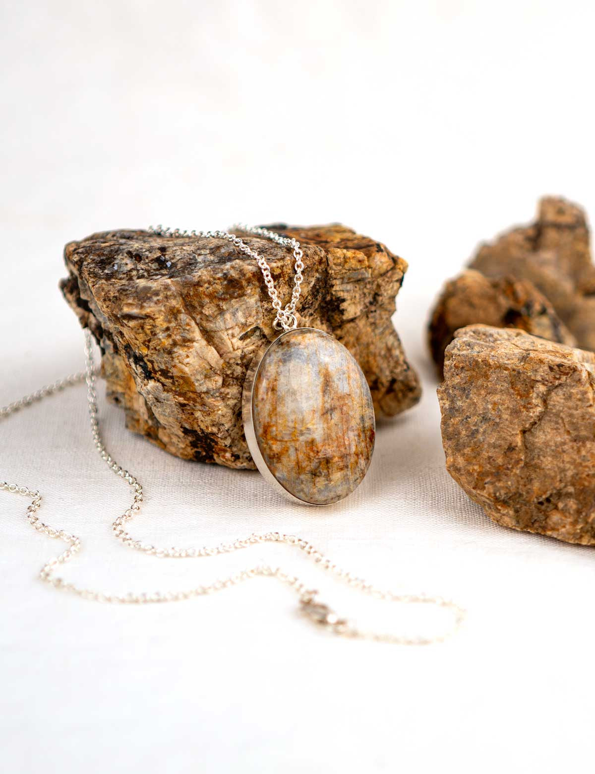 Sterling silver necklace with a large stone pendant made from feldspar surrounded by the rocks it was made from