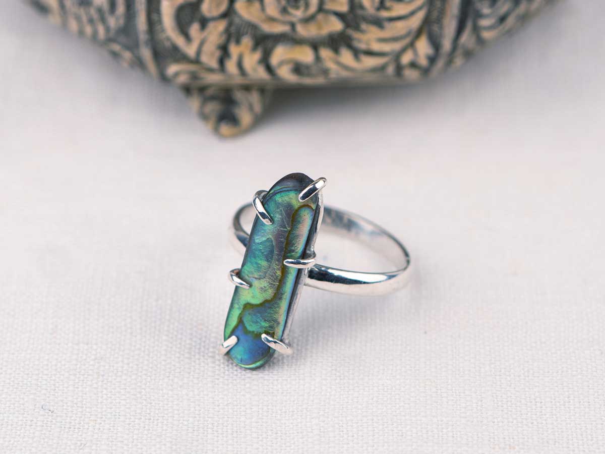A custom ring made with a teal shell set on a minimalist sterling silver band