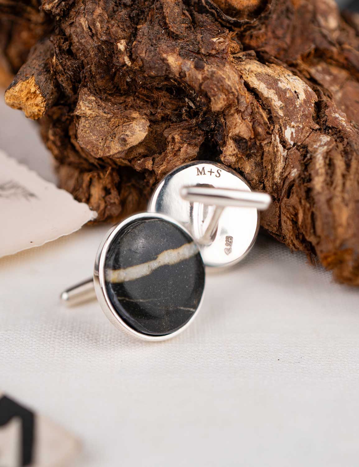 Sterling silver cufflinks made with a natural stone, one engraved on the back with the initial M+S