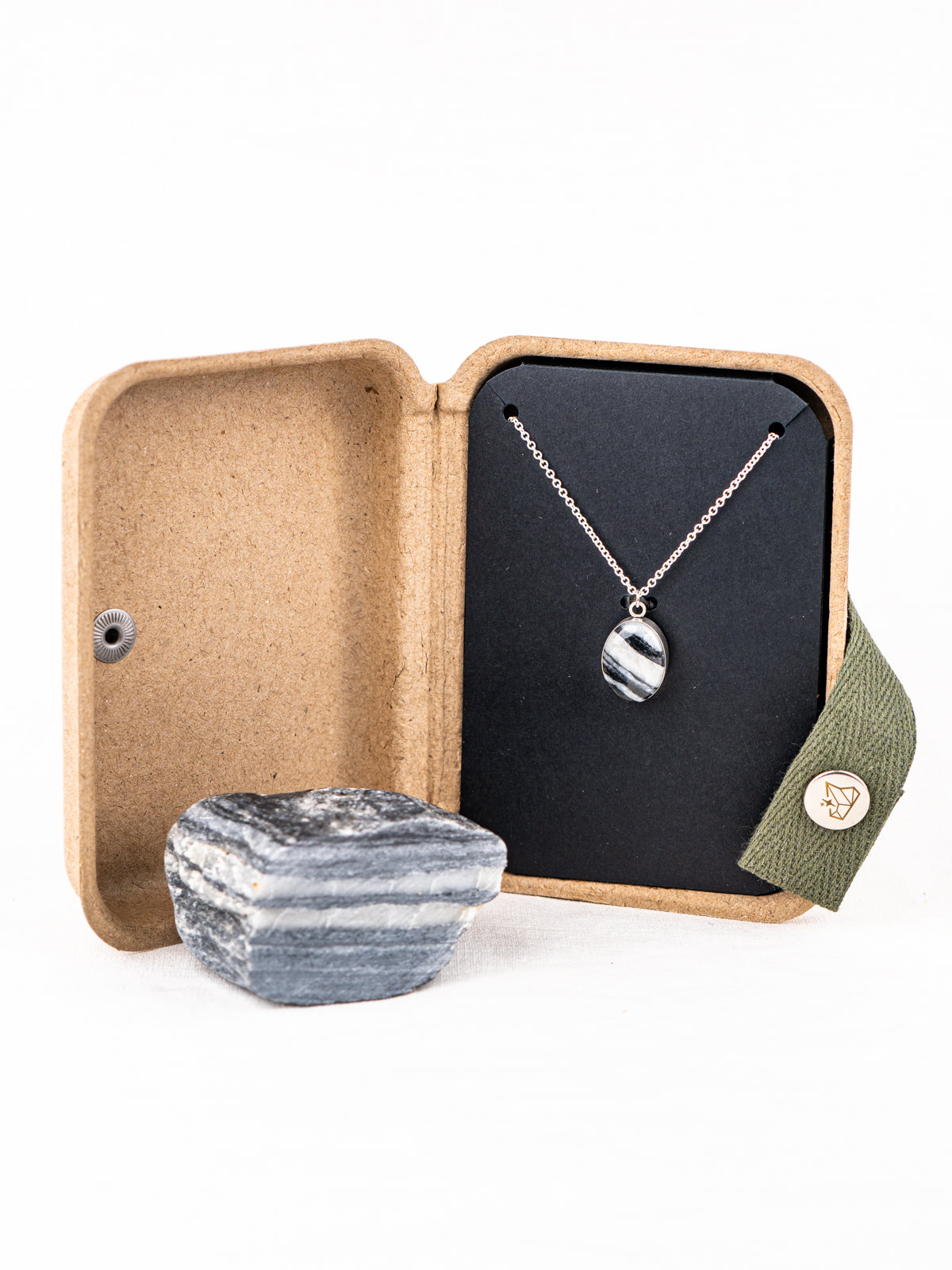 Silver stone pendant necklace with the original stone it was made from, displayed in a kraft jewelry box
