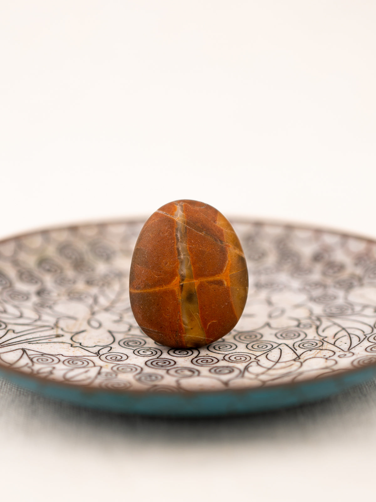 A smooth oval orange and black stone with interesting lines and stripes