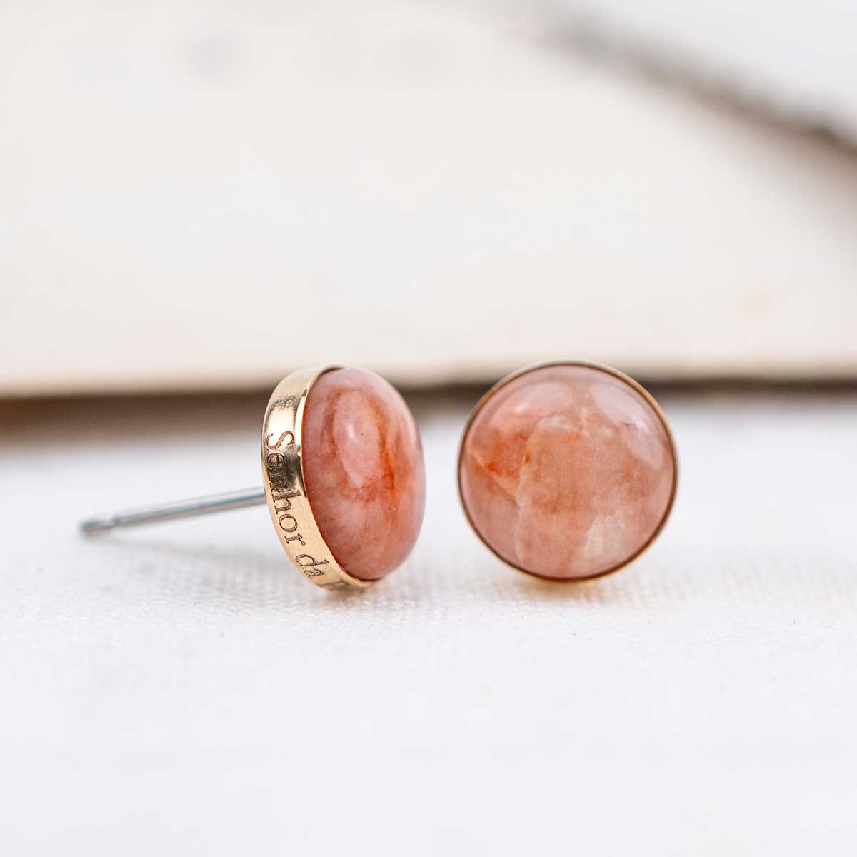 Pair of pink stone stud earrings with a gold setting custom engraved on the edge