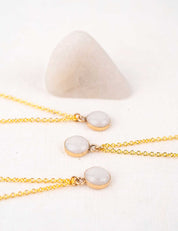 Three gold necklaces with white stone pendants and the rock they were made from