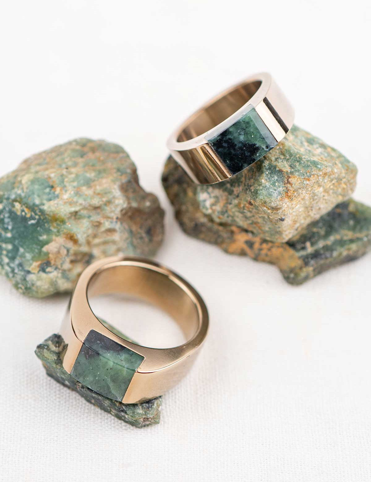 Two chunky champagne color stainless steel rings with matching natural green stones