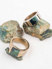 Two chunky champagne color stainless steel rings with matching natural green stones