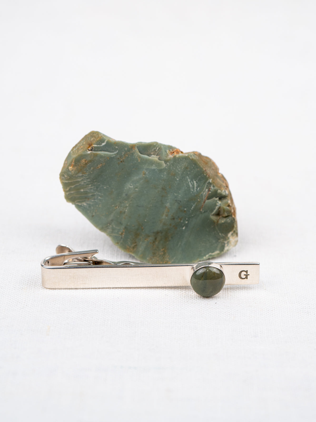 Tie clip with green stone next to original rock it was made from