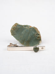 Tie clip with green stone next to original rock it was made from
