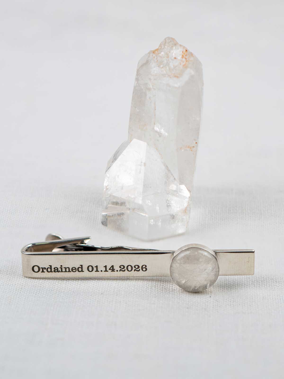 Quartz tie clip with engraved text on the front, with the rock it was made from