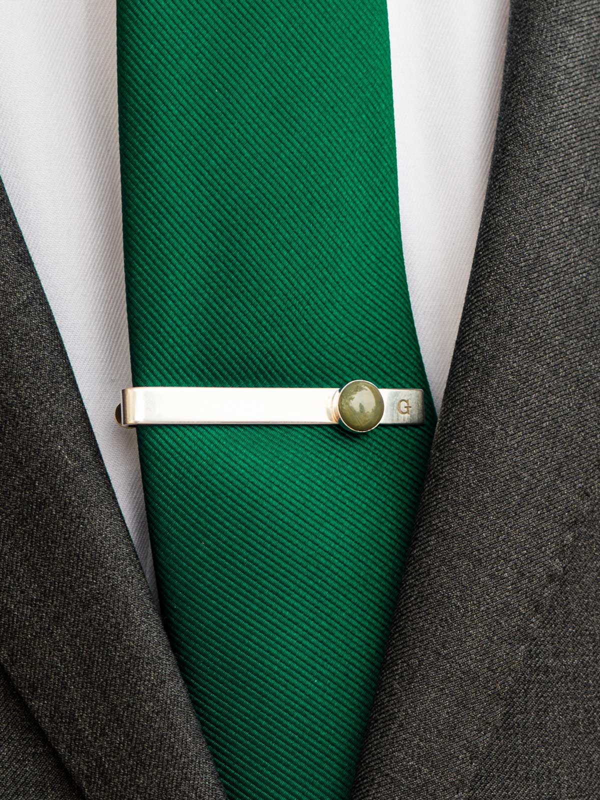 Green tie with a sterling silver tie clip set with a round green stone and custom engraved with the initial 'G'