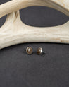 Pair of Smoky Quartz stud earrings on a dark surface with antler decor.