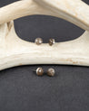 Sterling silver stud earrings set with gray smoky quartz stones on a dark surface with antlers in the background