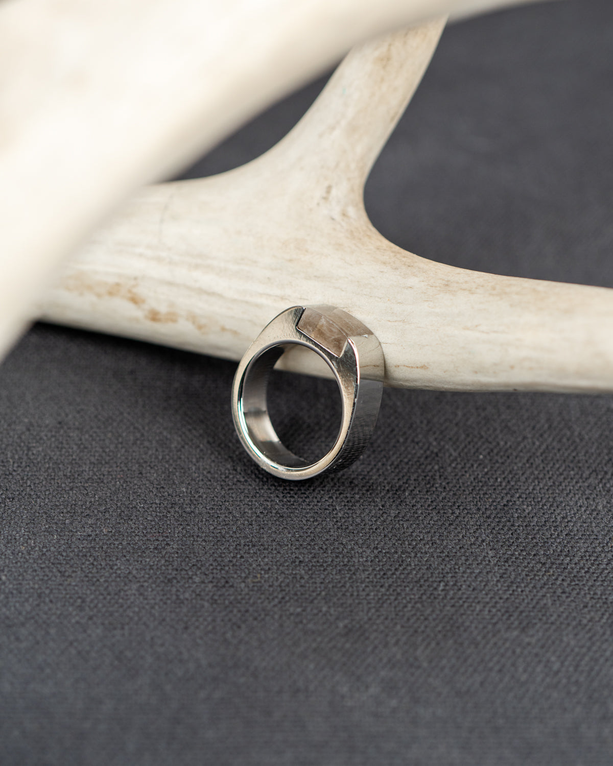 Silver ring set with a chunk of smoky quartz crystal on a deer antler against a dark background