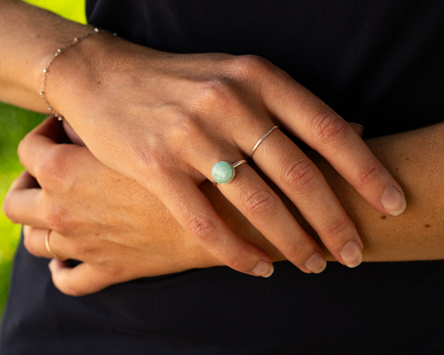 Close-up of a hand wearing a minimalist round stone ring set with Amazonite and made from sterling silver