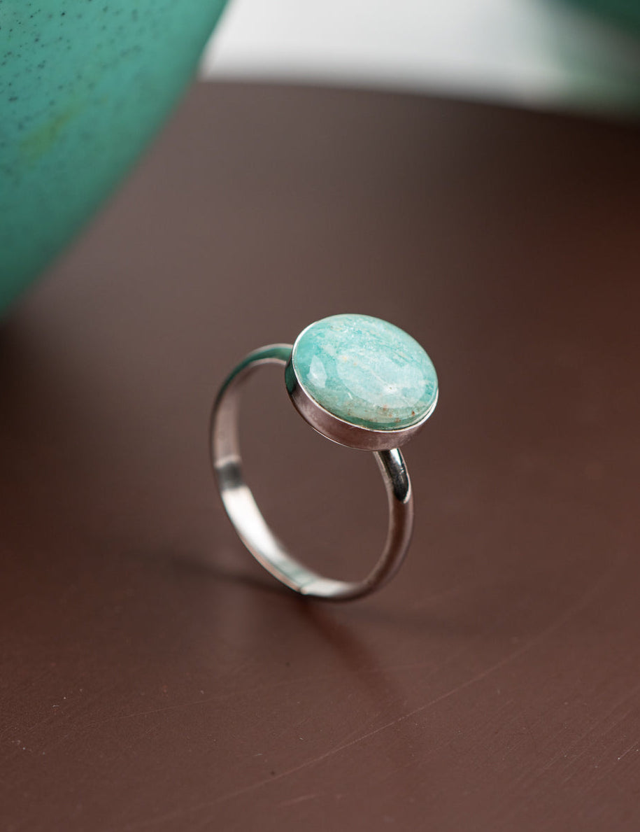 Sterling silver ring with a round Amazonite stone on a brown surface
