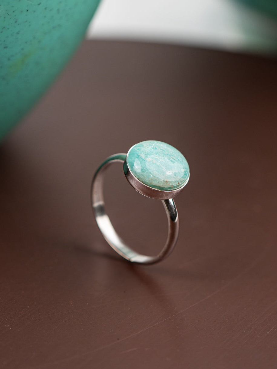 Sterling silver ring with a round Amazonite stone on a brown surface
