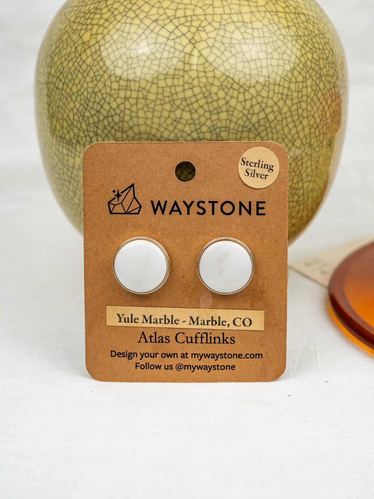 Waystone cufflinks packaging with a cracked vase in the background