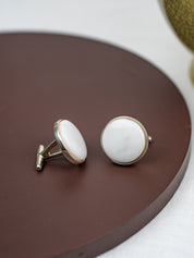 Pair of cufflinks with white stones on a brown circular surface