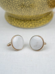 Pair of cufflinks with white stones and gold borders on a light background