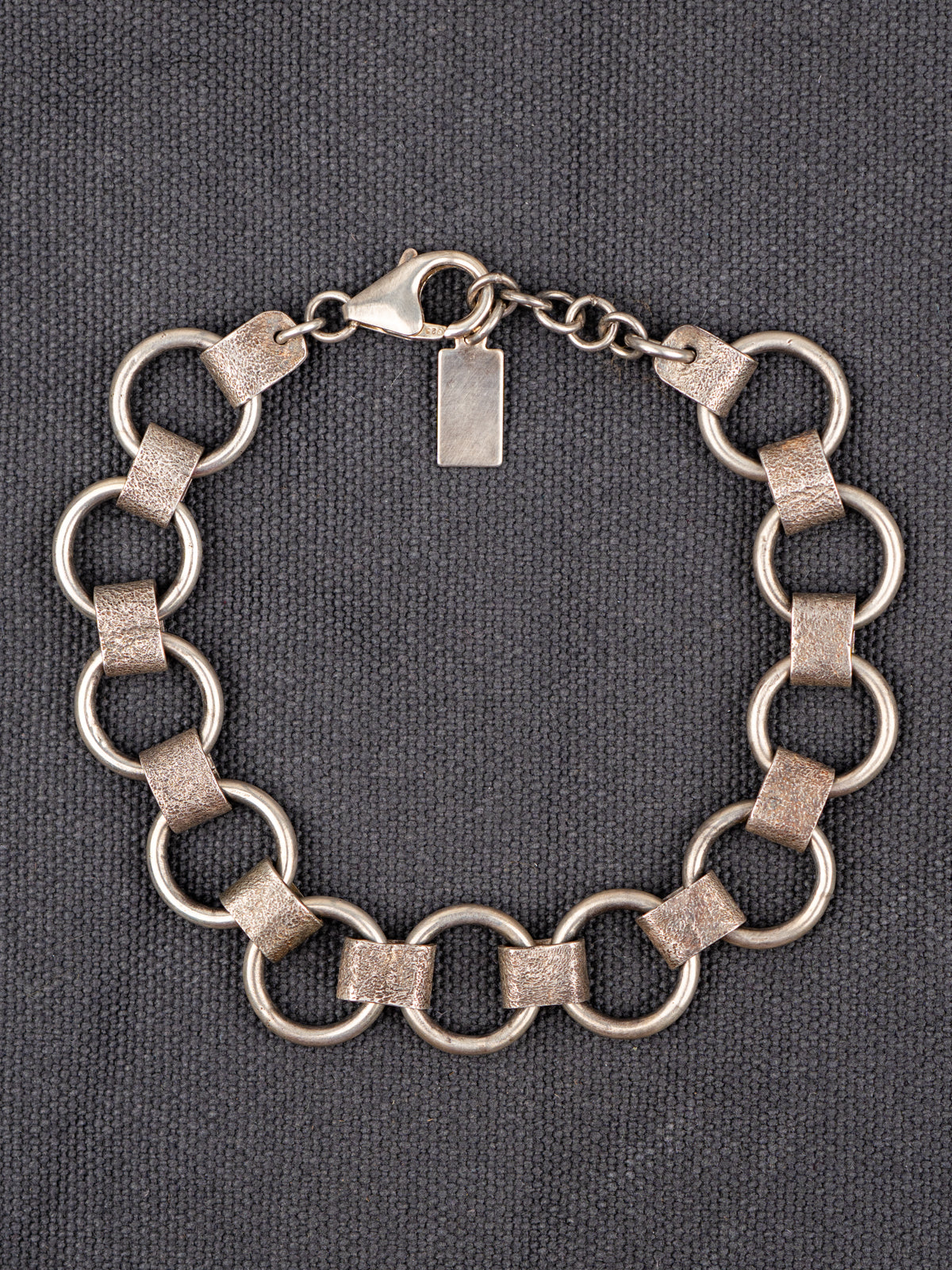 Sterling Silver hammered masculine bracelet on a gray fabric background