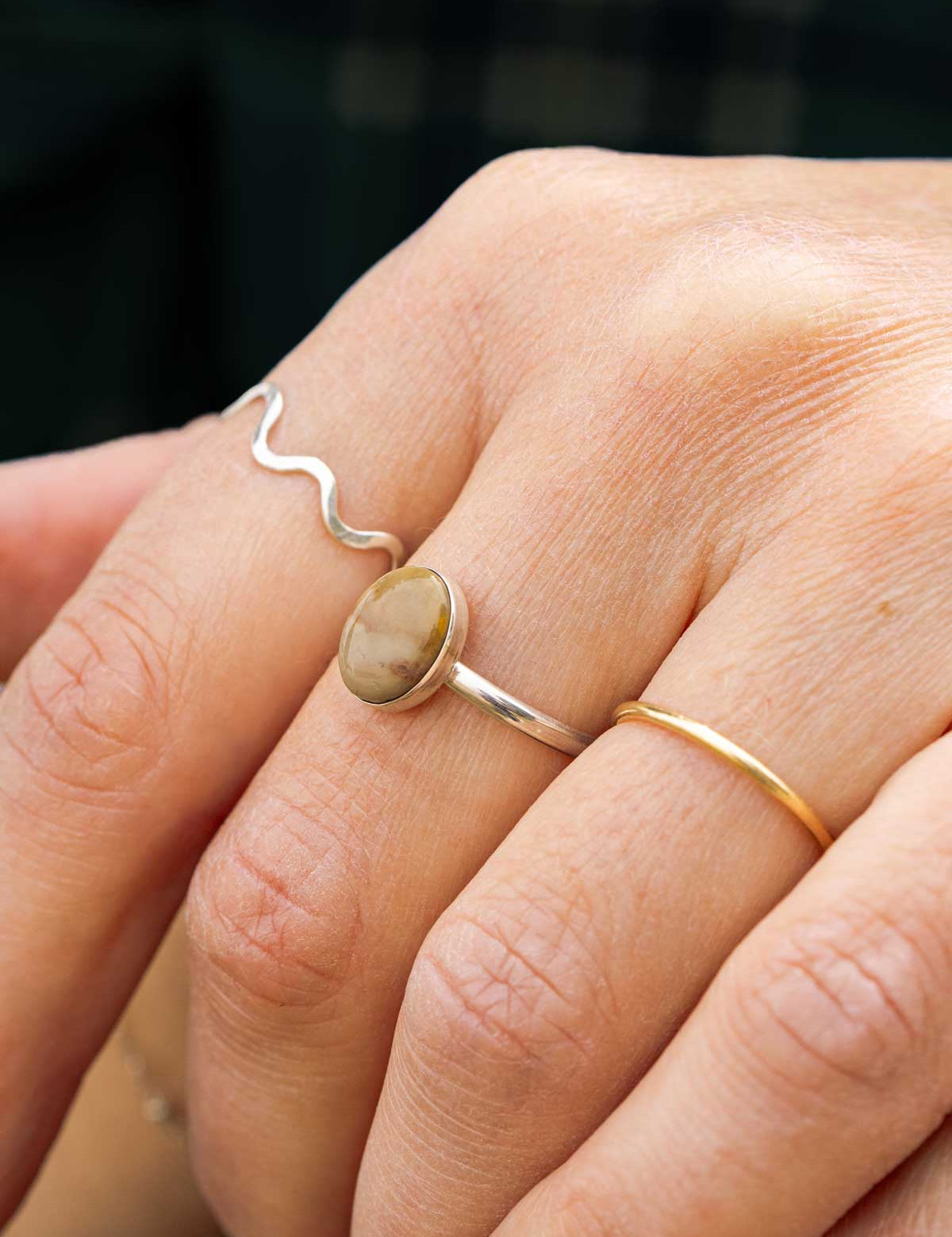 Close-up of a hand wearing a sterling silver ring set with a small oval stone