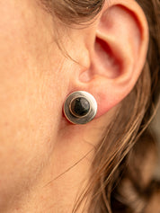 Sterling silver stud earring with a domed black jade stone, shown in close-up on a person's ear
