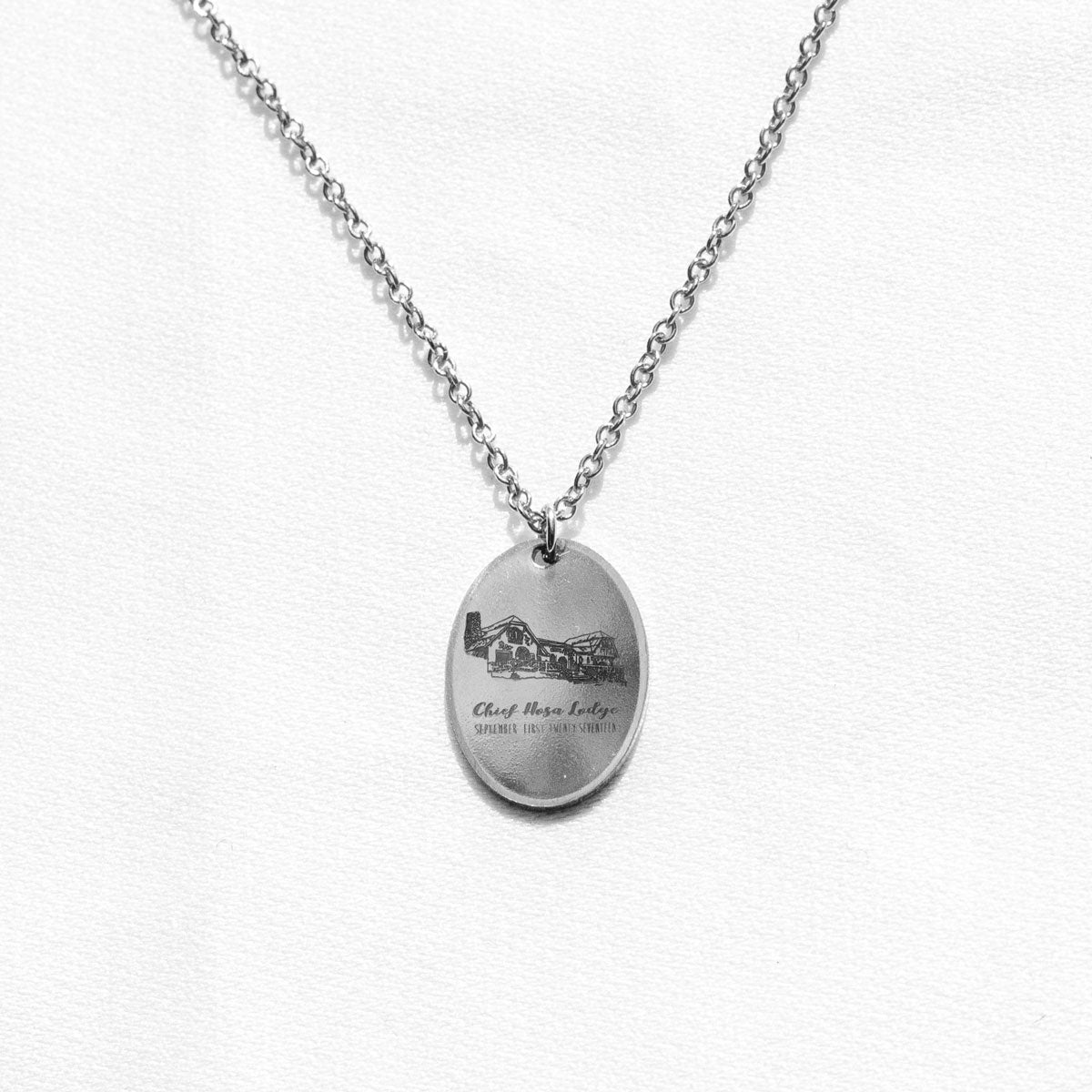 Oval silver charm necklace with an engraving of a wedding venue