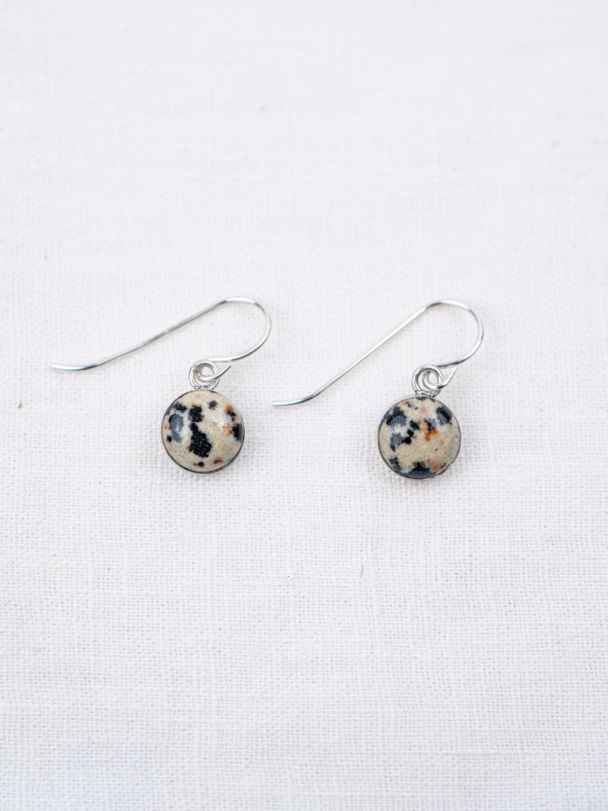 Pair of earrings with round, multicolored stones on a white background