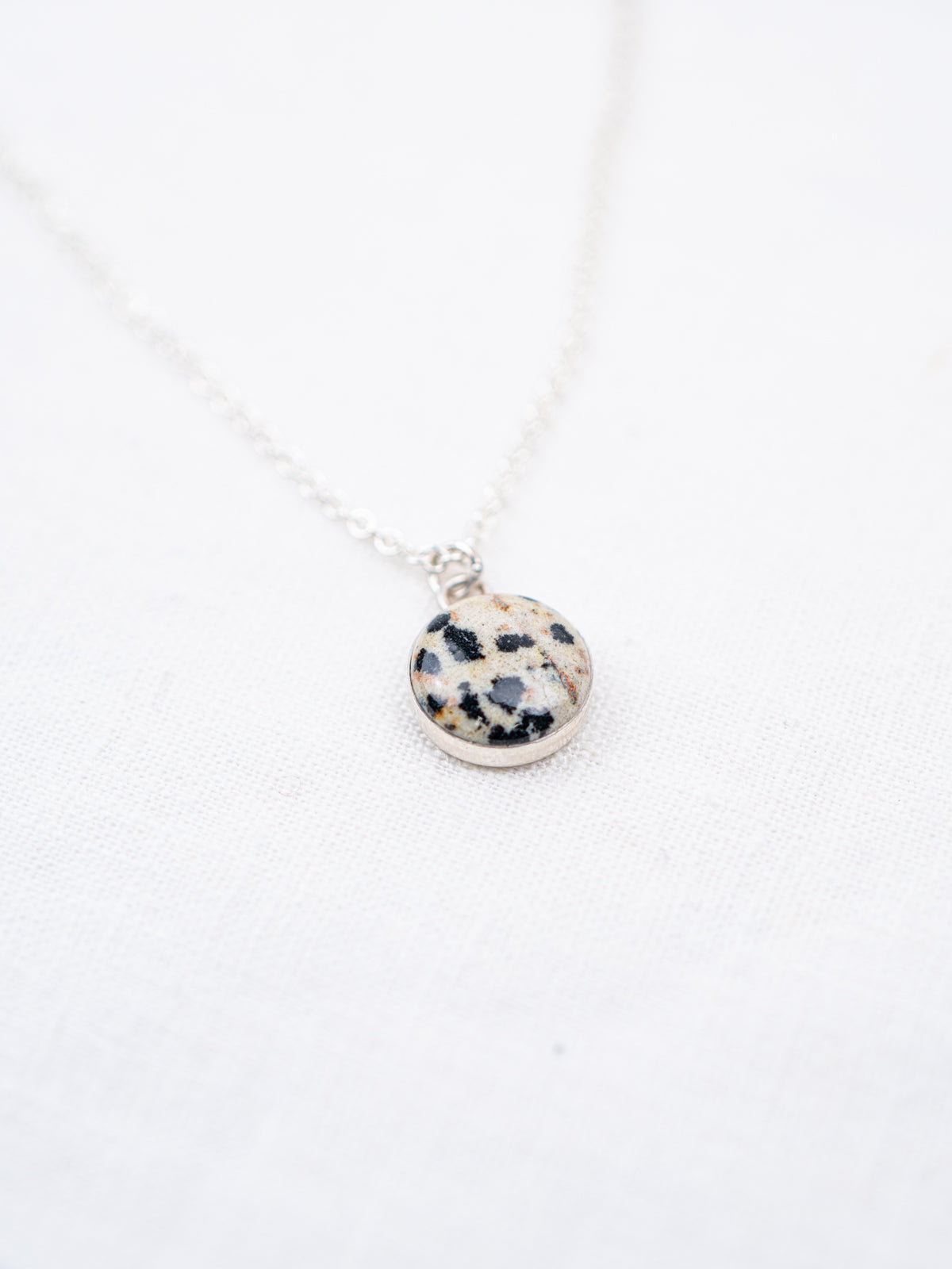 Necklace with a round pendant featuring black and white pattern on a white background