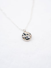 Necklace with a round pendant featuring black and white pattern on a white background