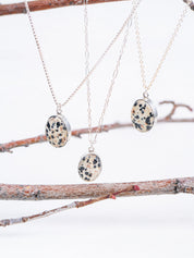 Three necklaces with dalmatian jasper pendants on a branch background