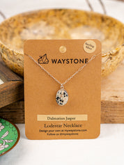 Waystone necklace on a brown card with a wooden bowl in the background