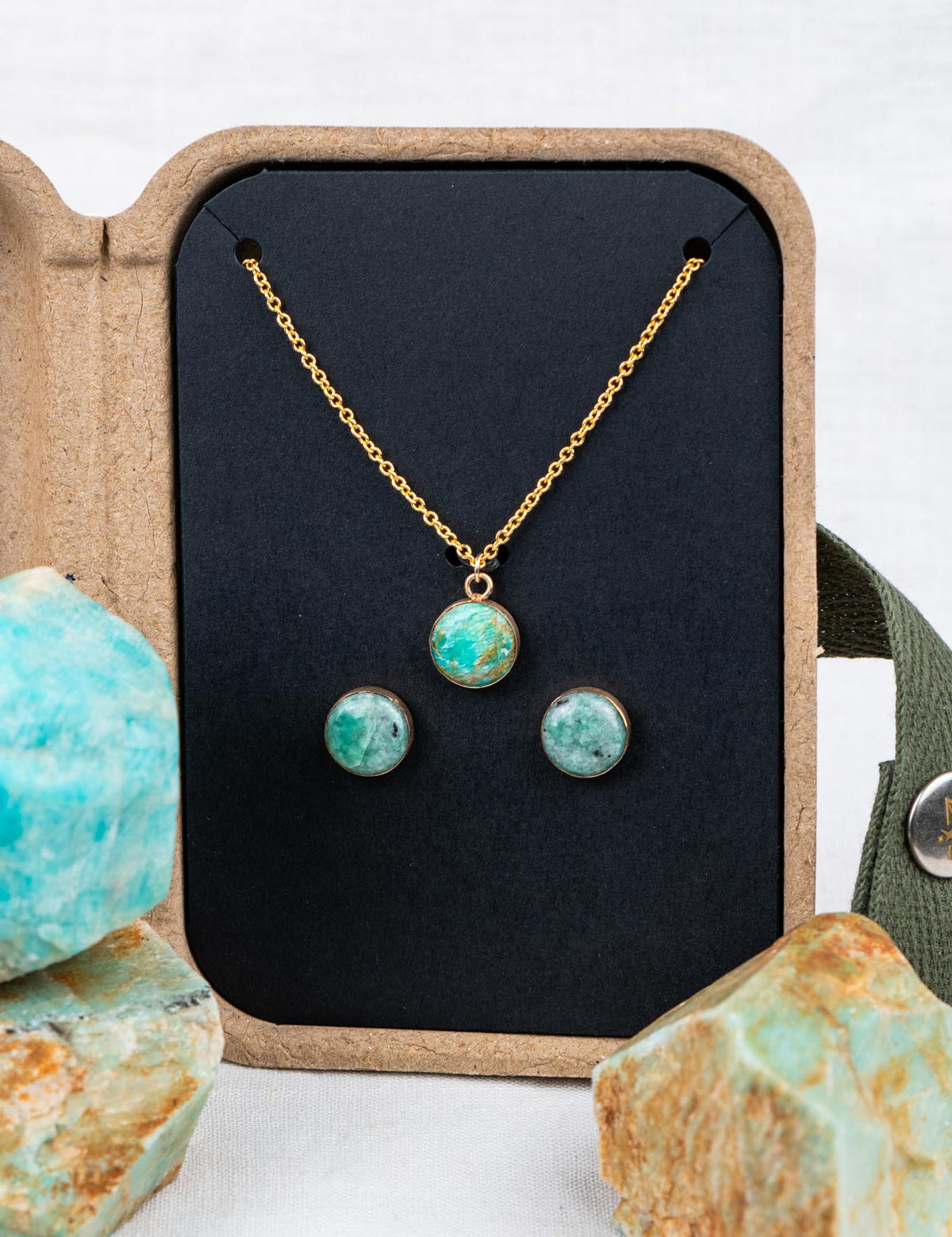 Stone jewelry set with necklace and earrings in a kraft gift box, surrounded by the rocks they were made from