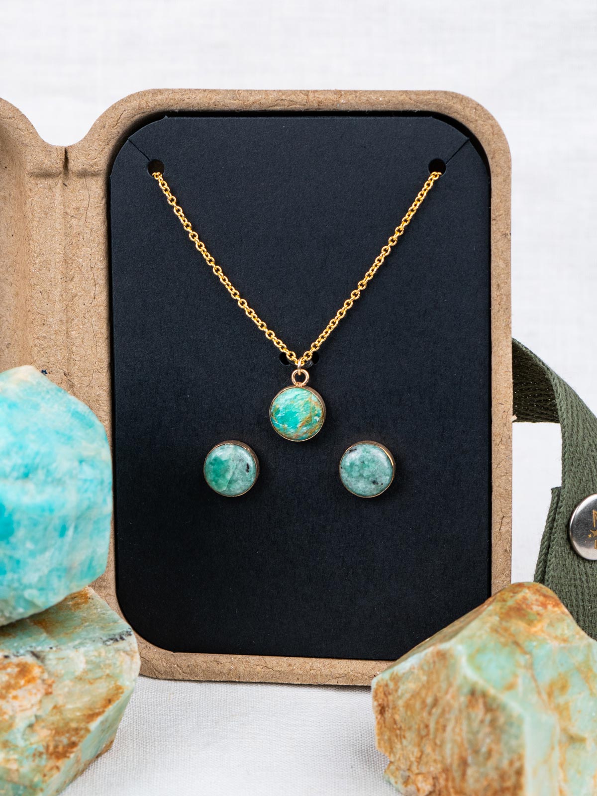 Stone jewelry set with necklace and earrings in a kraft gift box, surrounded by the rocks they were made from