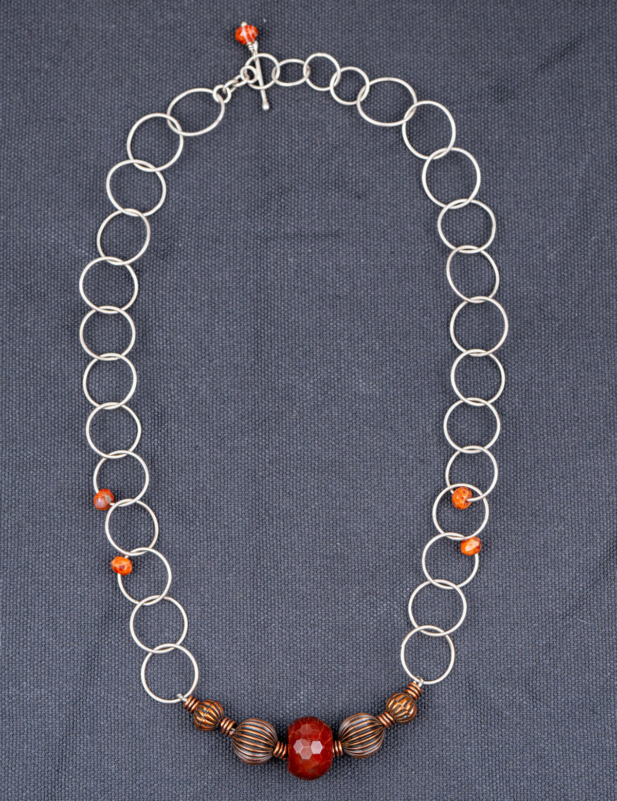 Sterling Silver Faceted Fire Agate necklace photographed on a gray background