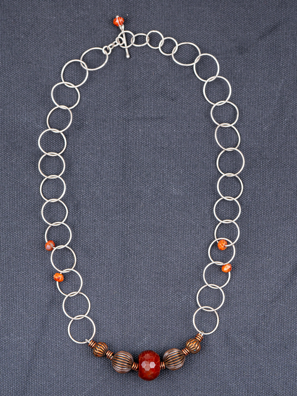 Sterling Silver Faceted Fire Agate necklace photographed on a gray background