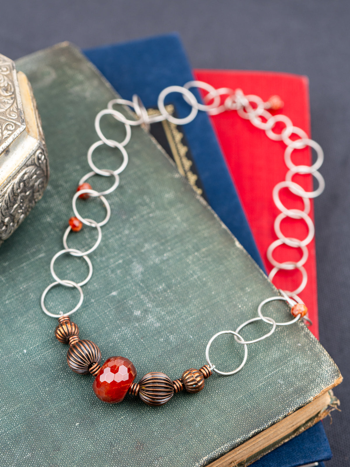 Sterling Silver Faceted Fire Agate with textured beads laid on books