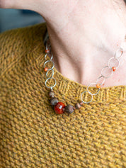 Sterling Silver Faceted Fire Agate photographed on a person with a textured yellow fabric
